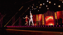 two women in lingerie are dancing on a stage in front of a mirror .
