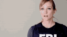a woman in a fbi vest is making a funny face .