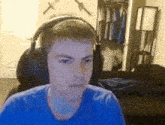 a boy wearing headphones and a blue shirt looks at the camera