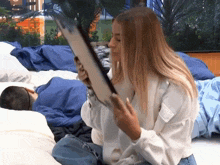 a woman sitting on a bed holding a picture