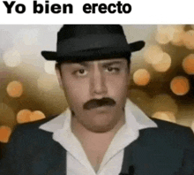 a man with a mustache and a hat is wearing a suit and a white shirt .