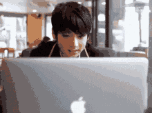a man wearing headphones is sitting in front of an apple laptop