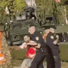 a police officer is holding a man in front of a tank .