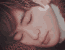 a close up of a person 's face with their eyes closed and a blurred background