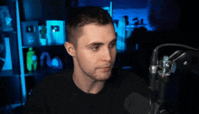a man in front of a microphone with his finger pointing to his face
