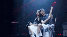 a girl holding a guitar while another girl looks on