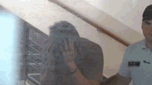 a man covering his face is being escorted by a police officer with a badge that says ' a. '