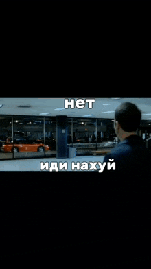 a man in a black shirt stands in front of a window with a car in the background and the words " het " in white