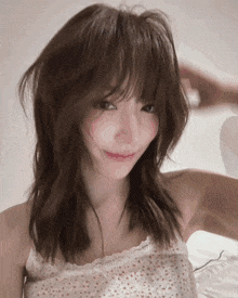 a woman wearing a white tank top with polka dots is smiling