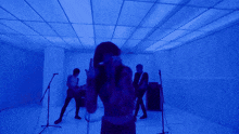 a person singing into a microphone in a room with blue lights