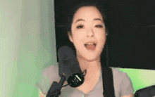 a woman is singing into a microphone while sitting in front of a green wall .