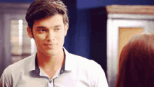 a man in a white shirt is smiling at a woman in a room .