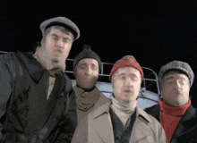 a group of men standing next to each other with one wearing a red hat with the letter r on it