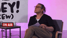 a woman is sitting in front of a sign that says hey
