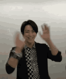 a man in a black and white checkered shirt is waving his hands .