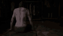 a man without a shirt is sitting on a bed in a dark room .