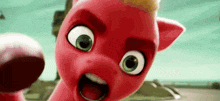a close up of a red cartoon pony with green eyes and a yellow mane making a funny face .