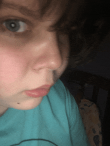 a close up of a woman 's face with a blue shirt on