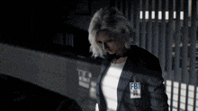 a woman wearing a fbi badge stands in a dark room