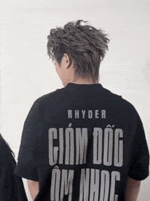 a man wearing a black shirt that says rhyder on the back