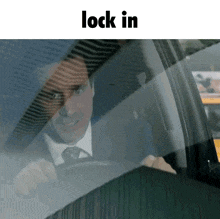 a man in a suit and tie is driving a car and the words lock in are below him