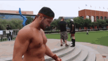 a shirtless man with a red headband is walking down a set of stairs
