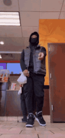 a man wearing a black mask is standing in a store