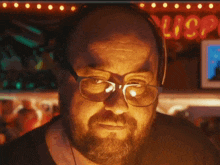 a man wearing glasses and headphones looks at the camera in front of a sign that says lisa