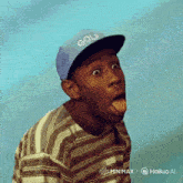 a man wearing a blue hat that says golf sticking out his tongue