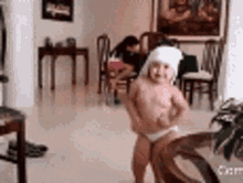 a little girl is dancing in a living room while wearing a santa hat .