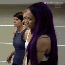 three women with purple hair are standing in a ring .