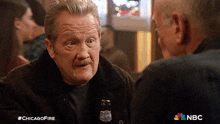 a man talking to another man with a bottle of beer on his collar
