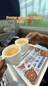 two cups of coffee sit on a tray that says meals where you sit