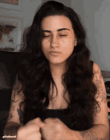 a woman with long dark hair and a tattoo on her arm