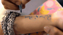 a person writing on another person 's arm with a marker that says returns rare