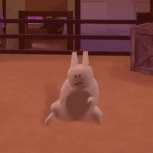 a white rabbit is sitting on the floor in a room with a fence in the background .