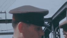 a man wearing a hat is standing in front of a metal structure .