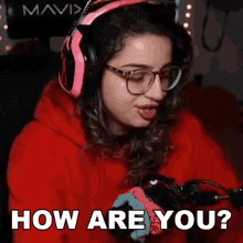 a woman wearing headphones and glasses is asking how are you while playing a video game .