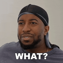 a man with a beard is wearing a head scarf and says " what "