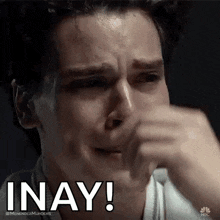 a man is crying and covering his face with his hand while saying inay !