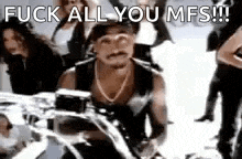 a man is riding a motorcycle with a group of people behind him and says `` fuck all you mfs ! ''