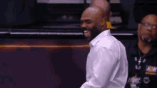 a man in a white shirt is smiling while watching a basketball game on tnt