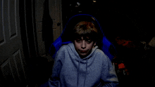 a boy wearing a grey hoodie has his mouth open