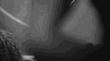 a black and white photo of a person standing in a dark room with a blurred background .