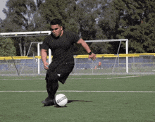 a man kicking a soccer ball on a field with the number 8 on the fence