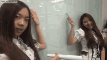 two girls are standing next to each other in front of a whiteboard .
