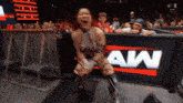 a woman in a wrestling ring is screaming in front of a sign that says aw