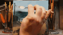 a hand is holding a spoon in front of a painting that says made in animonica