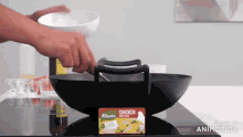 a person is cooking chicken in a wok on a stove top