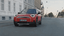 a red car with the license plate m ac 1367 e drives down a city street
